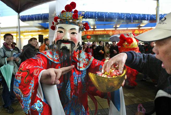 圖為1位民眾拿取財神爺發放的金元寶喜糖以沾財運。(圖/《中時電子報》 王錦河攝) 圖為1位民眾拿取財神爺發放的金元寶喜糖以沾財運。(圖/《中時電子報》 王錦河攝)