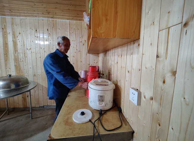 杉板裝飾的屋內(nèi),老黨員正熱情地給客人們倒茶。徐俊聰攝