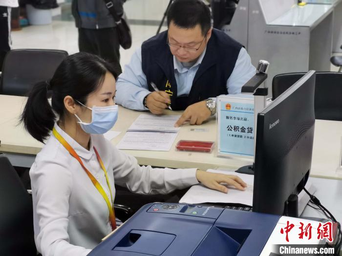 廣西壯族自治區區直住房公積金管理中心工作人員為梁洲輔辦理公積金貸款。 蔣雪林 攝