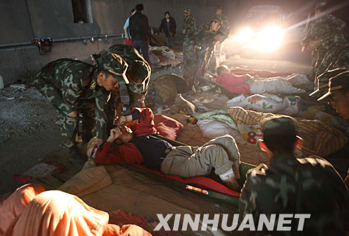 5月21日,武警官兵在蟠龍山隧道救護(hù)傷員。當(dāng)日,武警四川總隊總隊長王佐明帶領(lǐng)特警隊員乘坐直升機(jī)前往汶川縣映秀鎮(zhèn),營救被困在蟠龍山隧道和耿達(dá)電站中的受傷群眾。因蟠龍山地形復(fù)雜,直升機(jī)在峽谷中盤旋半個小時找不到降落點(diǎn),武警官兵采取繩降、跳降結(jié)合方式,從空中懸停直升機(jī)上跳下開展搜救行動。