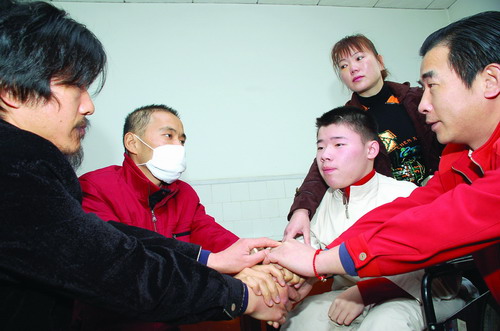 4月5日,黃舸父子(右一、二)和黃學文(左一)來到湘雅附一醫院看望黃國雄(左二),相似的經歷讓四個人的手緊緊地握在了一起。圖/陳正